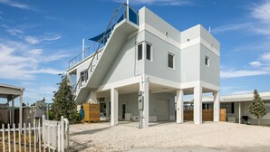 Un edificio moderno de dos pisos con un espacio exterior cubierto y una escalera que conduce al piso superior.