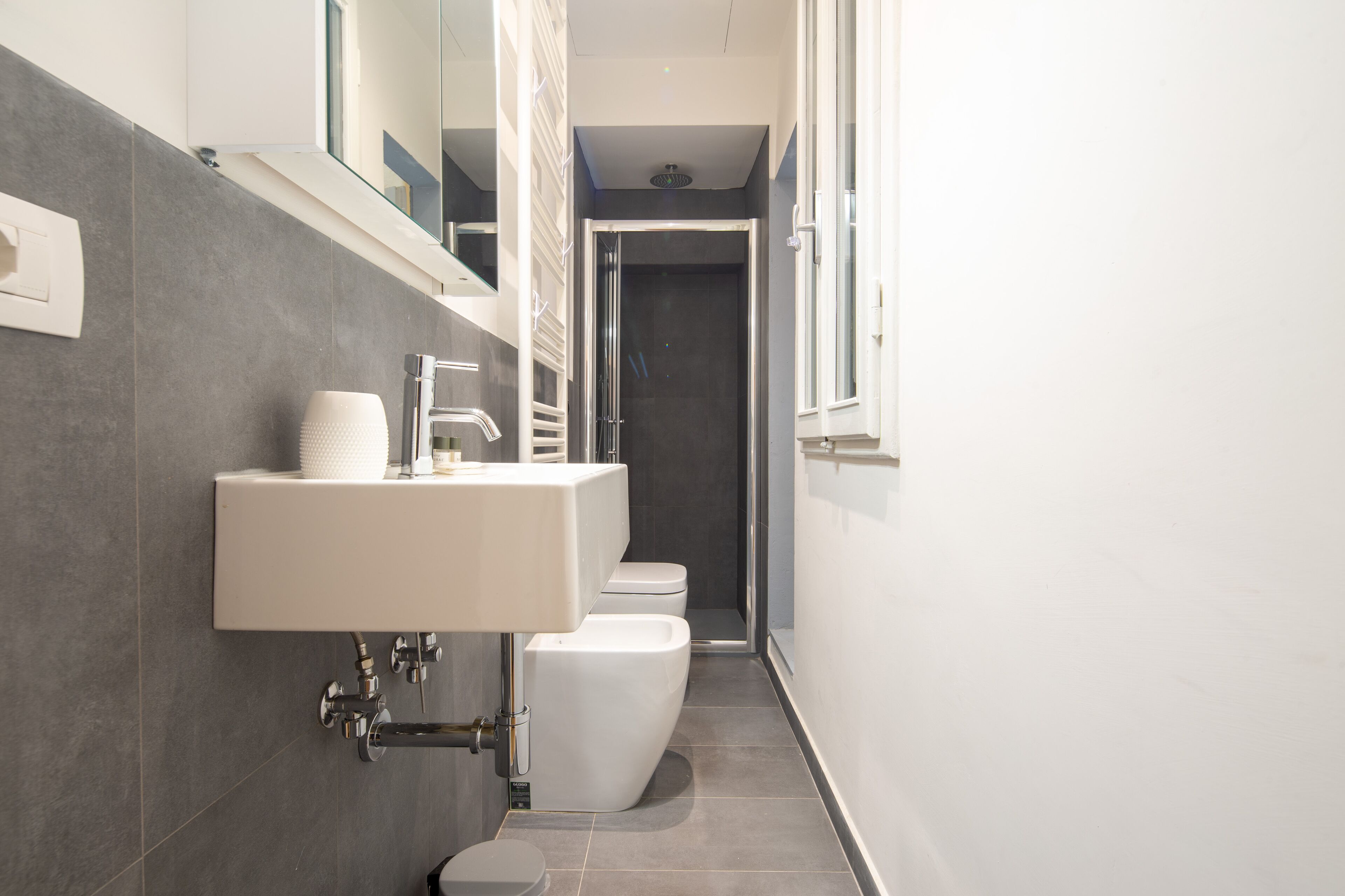 A modern bathroom with a white sink, a toilet, and a shower.