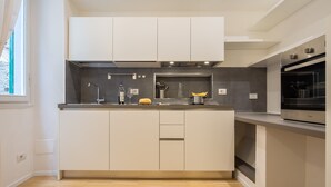 Eine moderne Küche mit weißen Schränken, einem eingebauten Backofen und einer großen Kochinsel mit Spüle.