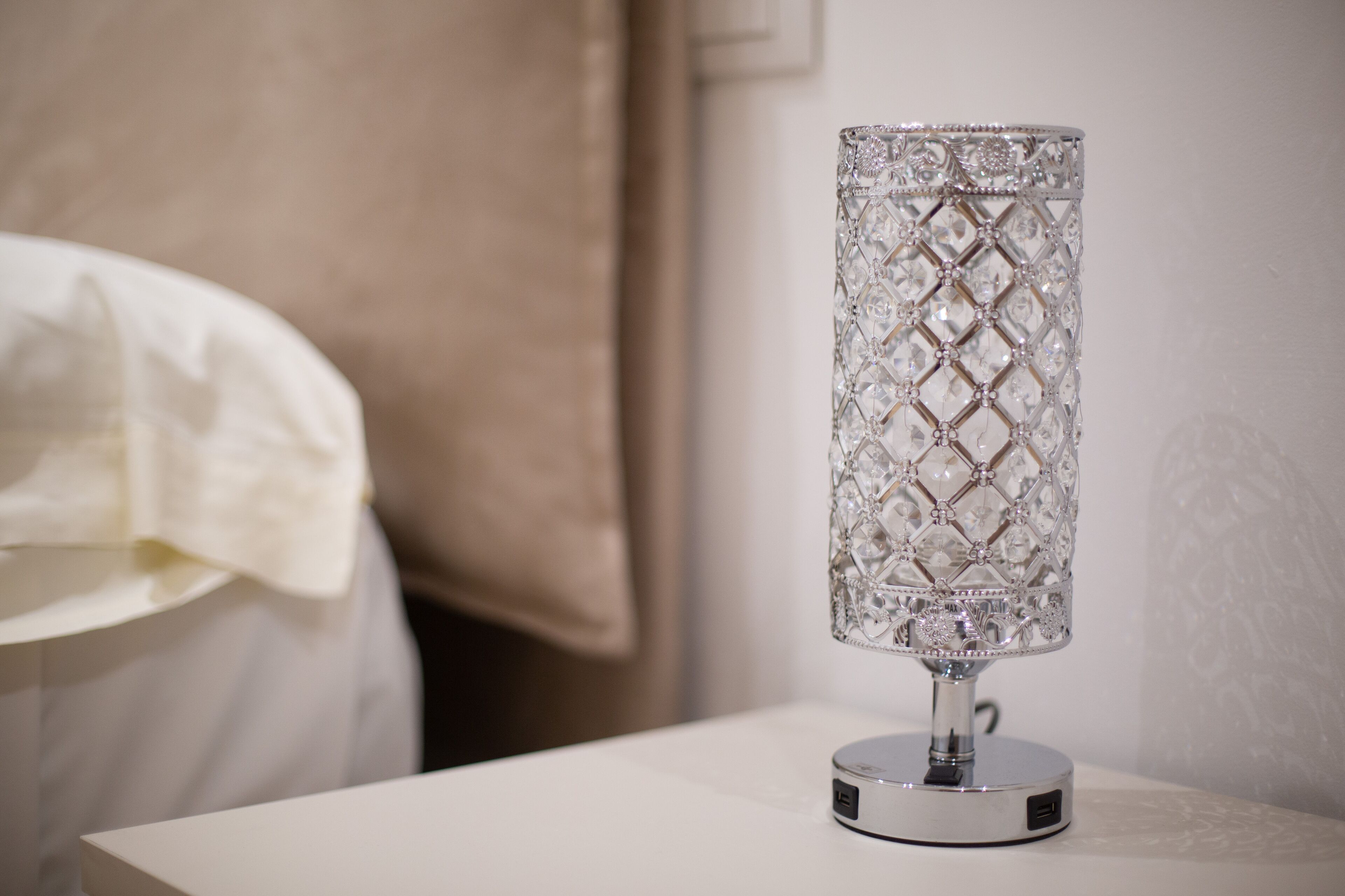 A crystal lamp on a white bedside table in a hotel room.