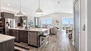 A modern kitchen with a central island, stainless steel appliances, and pendant lighting.