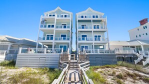 A multi-story beachfront hotel with a central staircase leading to the entrance.