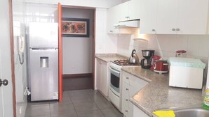 A compact kitchen with a refrigerator, stove, and sink. - Suite Miraflores. A. (Urb Cercado de Miraflores)