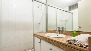 A bathroom with a shower, a sink, a mirror, and a towel. - Suite Miraflores. A. (Urb Cercado de Miraflores)