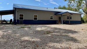 A single-story building with a covered outdoor area, a gravel driveway, and a clear sky.