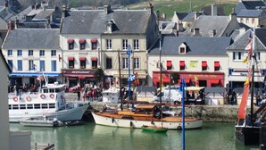 A harbor with boats, a café, and a restaurant. - Large bright house in the shape of a boat (Port-en-Bessin-Huppain)