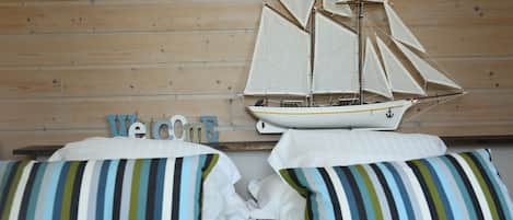 A bed with striped pillows and a sailboat model on the headboard.