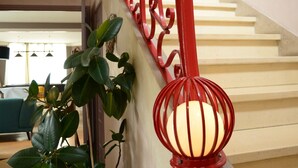 A staircase with a red railing, a potted plant, and a decorative light fixture. - Large bright house in the shape of a boat (Port-en-Bessin-Huppain)