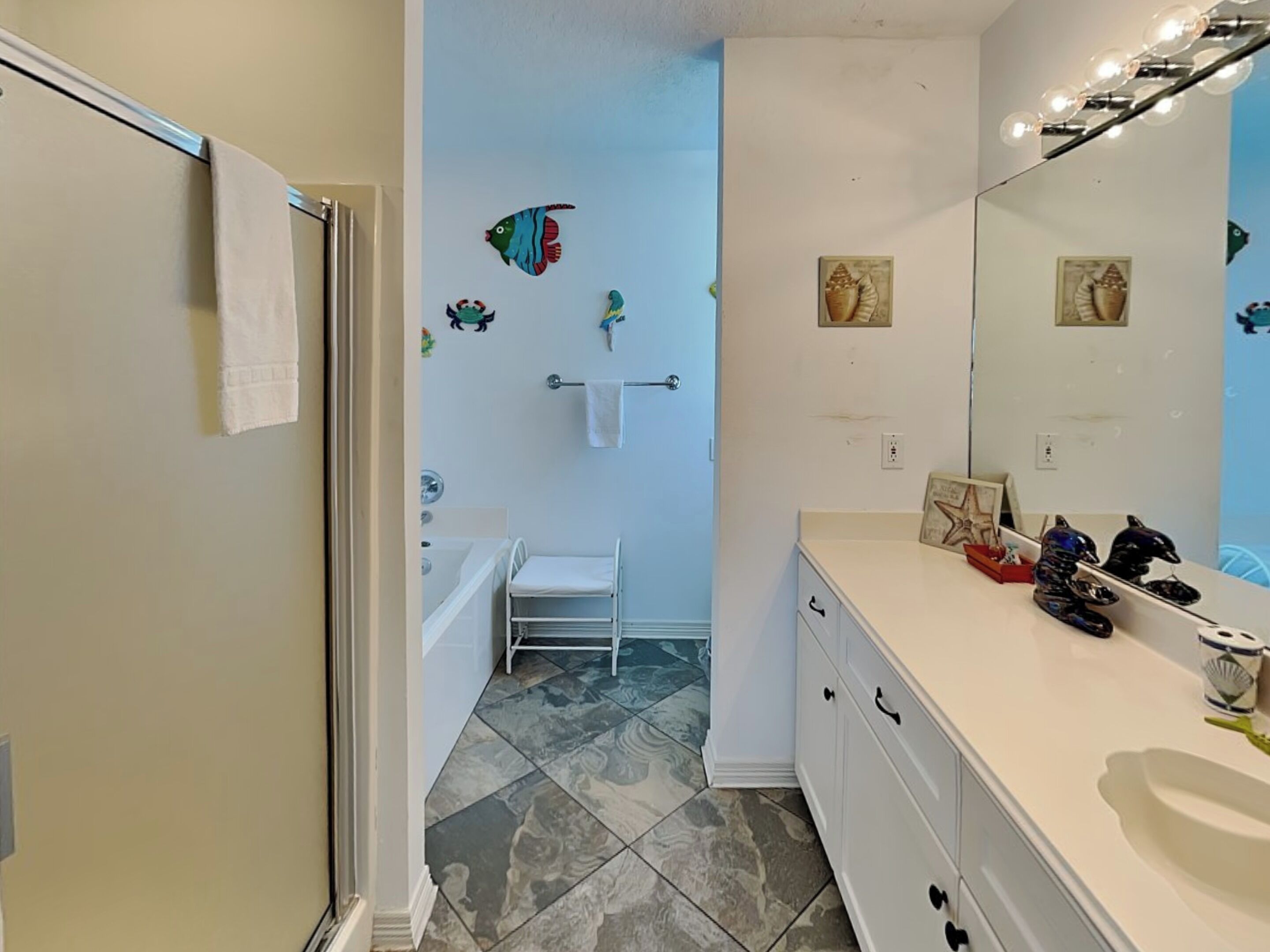 A bathroom with a white vanity, a bathtub, and a shower.