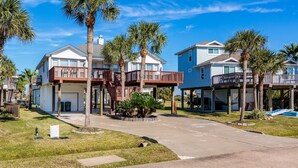 A beachfront property with two-story houses featuring balconies, a swimming pool, and palm trees.