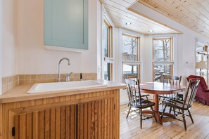 Une cuisine avec un îlot central en bois, un évier et un coin repas comprenant une table et des chaises.