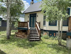 A house with a wooden deck, a front door, and a chimney.