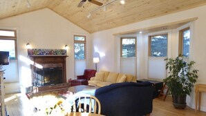 A cozy living room with a fireplace, a sofa, a dining table with chairs, and a ceiling fan. - Wildflower House - Silverton Victorian (Silverton)