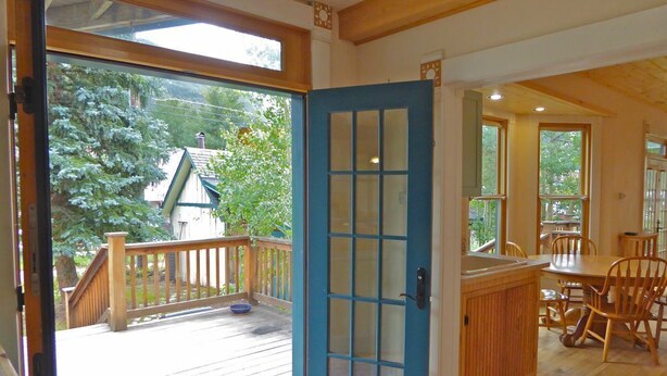 A wooden deck with a blue door leading to a dining area with a wooden table and chairs. - Wildflower House - Silverton Victorian (Silverton)