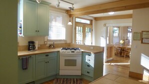A kitchen with teal cabinets, a stove, and a coffee maker. - Wildflower House - Silverton Victorian (Silverton)