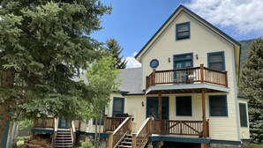 A two-story house with a balcony, wooden stairs, and a covered porch. - Wildflower House - Silverton Victorian (Silverton)