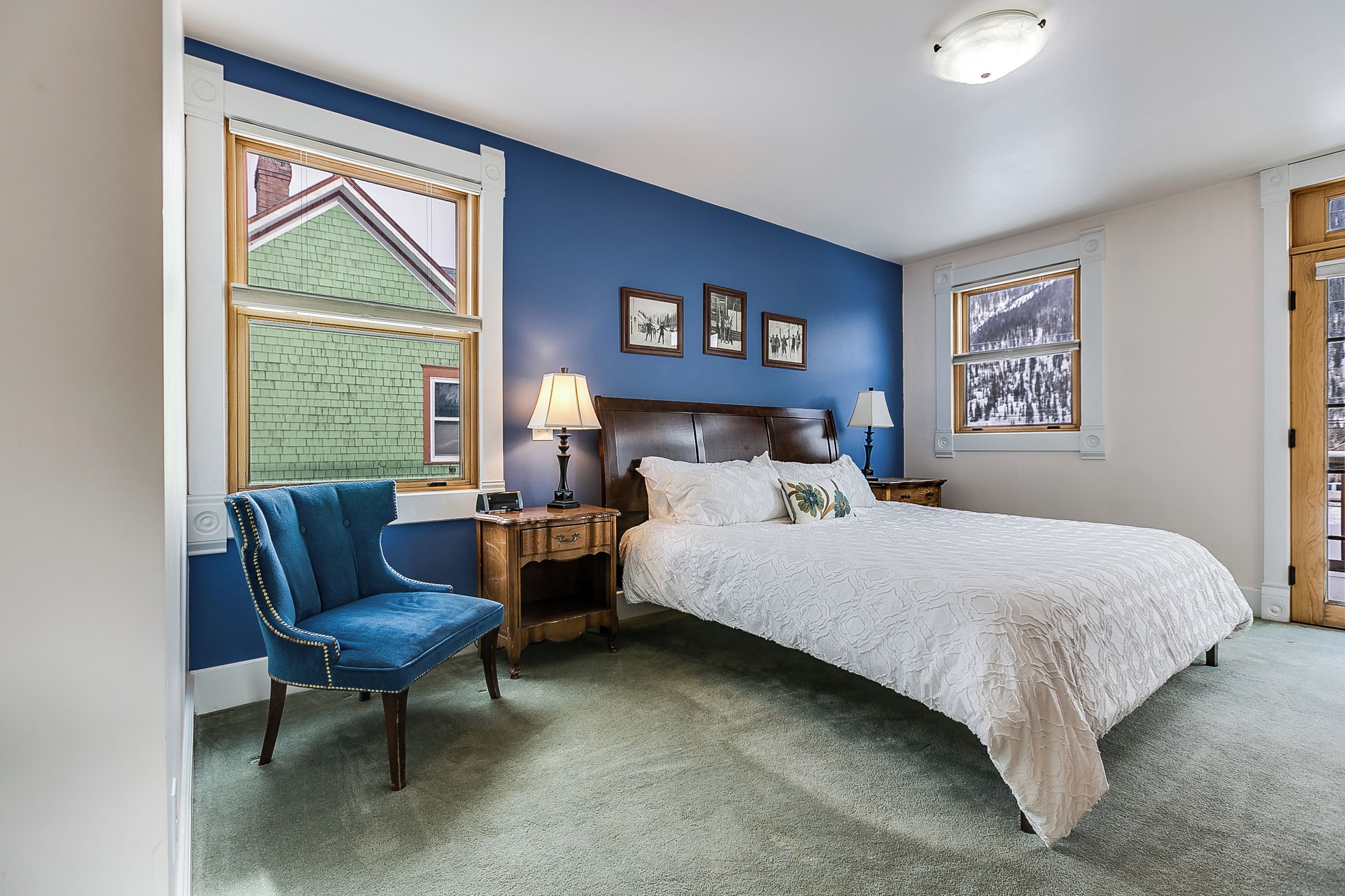 A bedroom with a large bed, a chair, a nightstand, and a window with a view of a building.