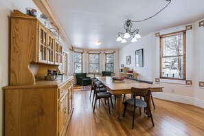 Un vaste espace dédié à la salle à manger, avec une longue table en bois, de nombreuses chaises et un lustre.