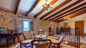 A rustic interior with stone walls, wooden beams, and a dining area with rocking chairs and a table. - QUIET RURAL HOUSE (San Juan)