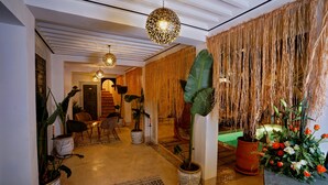 A hallway with a patterned rug, potted plants, hanging lights, and a decorative wall. - Riad Sokera Hotel & Spa - Adults Only (Marrakech)