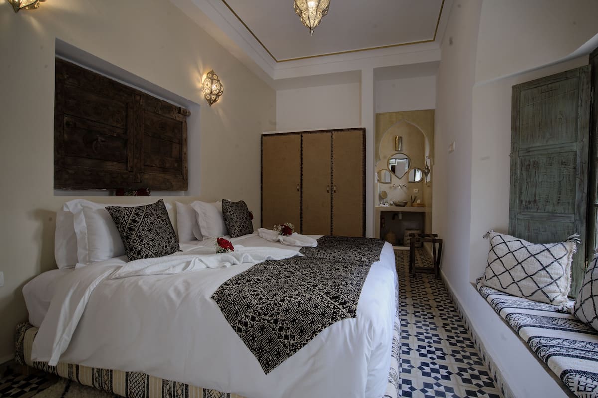 A bedroom with a large bed, a sofa, a wardrobe, and a mirror.