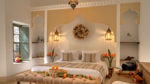 A well-appointed bedroom with a large bed, bedside lamps, a decorative wall piece, and a small table with a basket of fruit and flowers. - Riad Sokera Hotel & Spa - Adults Only (Marrakech)