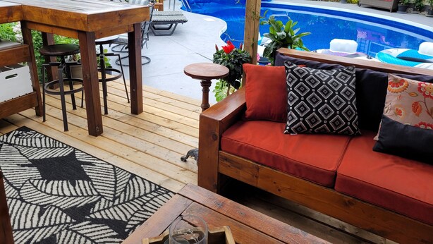 A wooden deck with a pool, outdoor furniture, and lush greenery. - Luxury home backyard paradise, salt water pool heated May to Oct. . 3bdrm 2 bath (Lindsay)