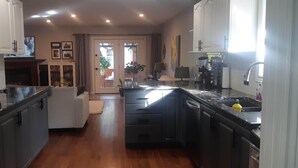 A modern kitchen with a central island, built-in appliances, and a dining area with a sofa. - Luxury home backyard paradise, salt water pool heated May to Oct. . 3bdrm 2 bath (Lindsay)