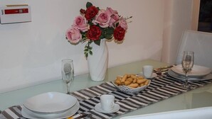Ett matbord dukat med tallrikar, skålar, glas och en vas med blommor.