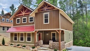 A two-story house with a porch, stone pillars, and a red awning. - Head Over Hills (Gatlinburg)