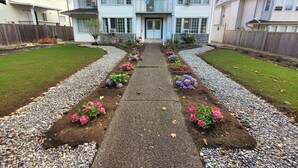 A two-story house with a stone foundation, a front porch, and a driveway leading to the entrance. - Modern, clean & private 1BR suite. Up to 4 guests. (Surrey)