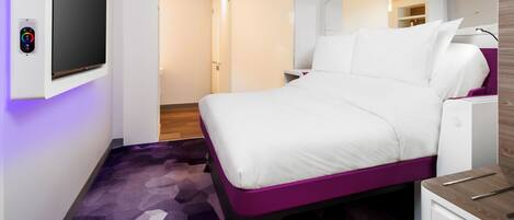 Een moderne hotelkamer met een bed, een televisie en een bureau.