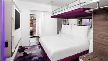 A modern hotel room with a bunk bed, a flat-screen TV, and a patterned carpet.