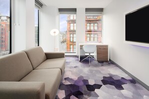 Una habitación moderna con sofá, escritorio y televisor.