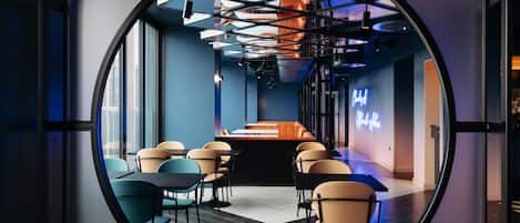 Un intérieur moderne doté d’un espace circulaire offrant une vue panoramique, de sièges, de tables et d’un panneau lumineux au néon.