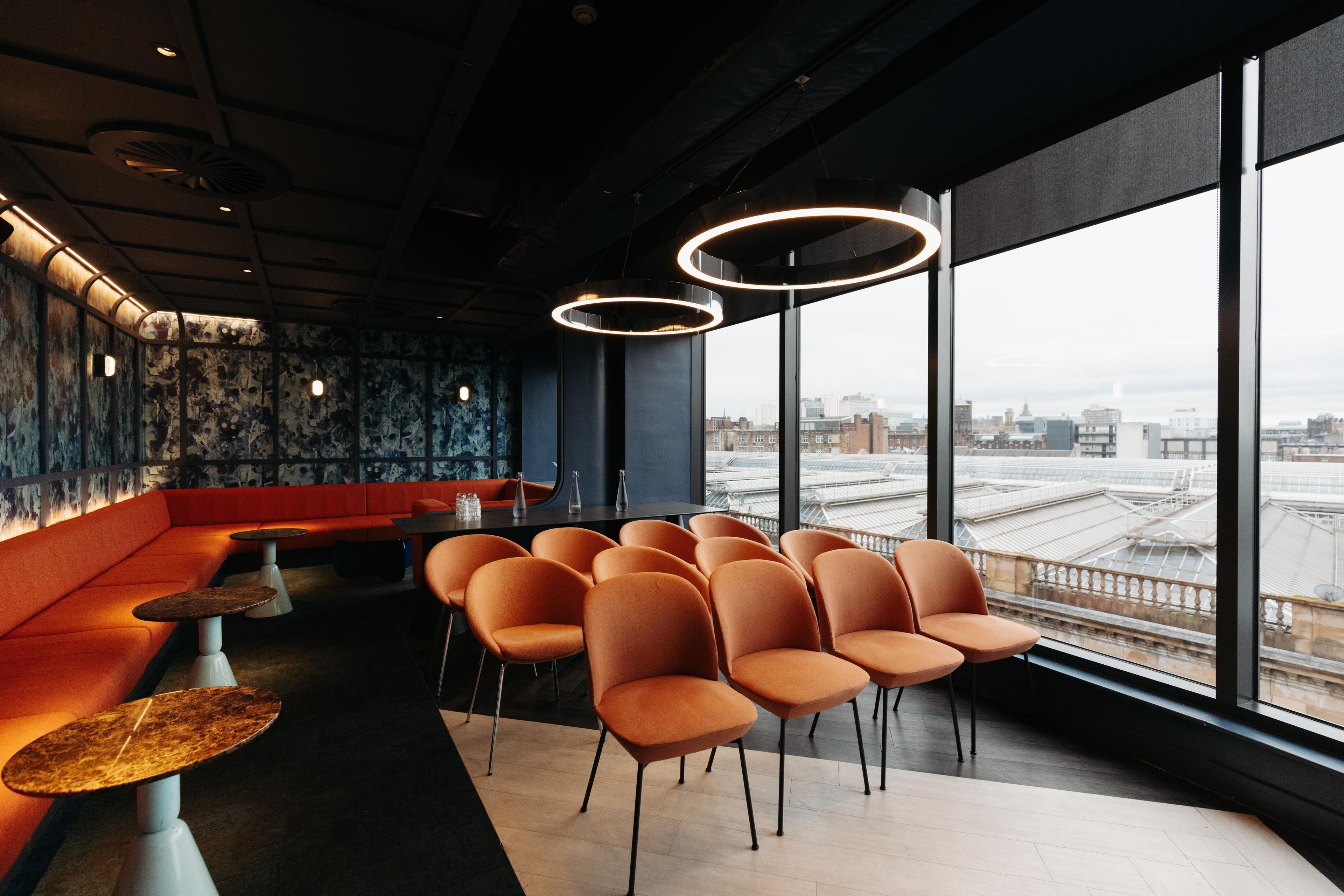 Un intérieur moderne comprenant un espace salon, un bar et de grandes fenêtres donnant sur la ville.
