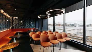 Un intérieur moderne comprenant un espace salon, un bar et de grandes fenêtres donnant sur la ville.
