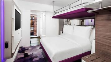 A modern hotel room with a bunk bed, a flat-screen TV, and a patterned carpet.