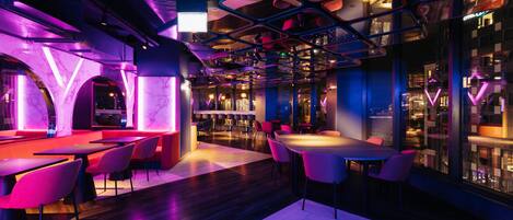 Een modern interieur met een bar, zitplaatsen en uitzicht door grote ramen.