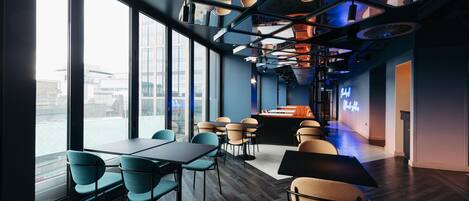 A modern interior with large windows, a bar area, and seating arrangements.