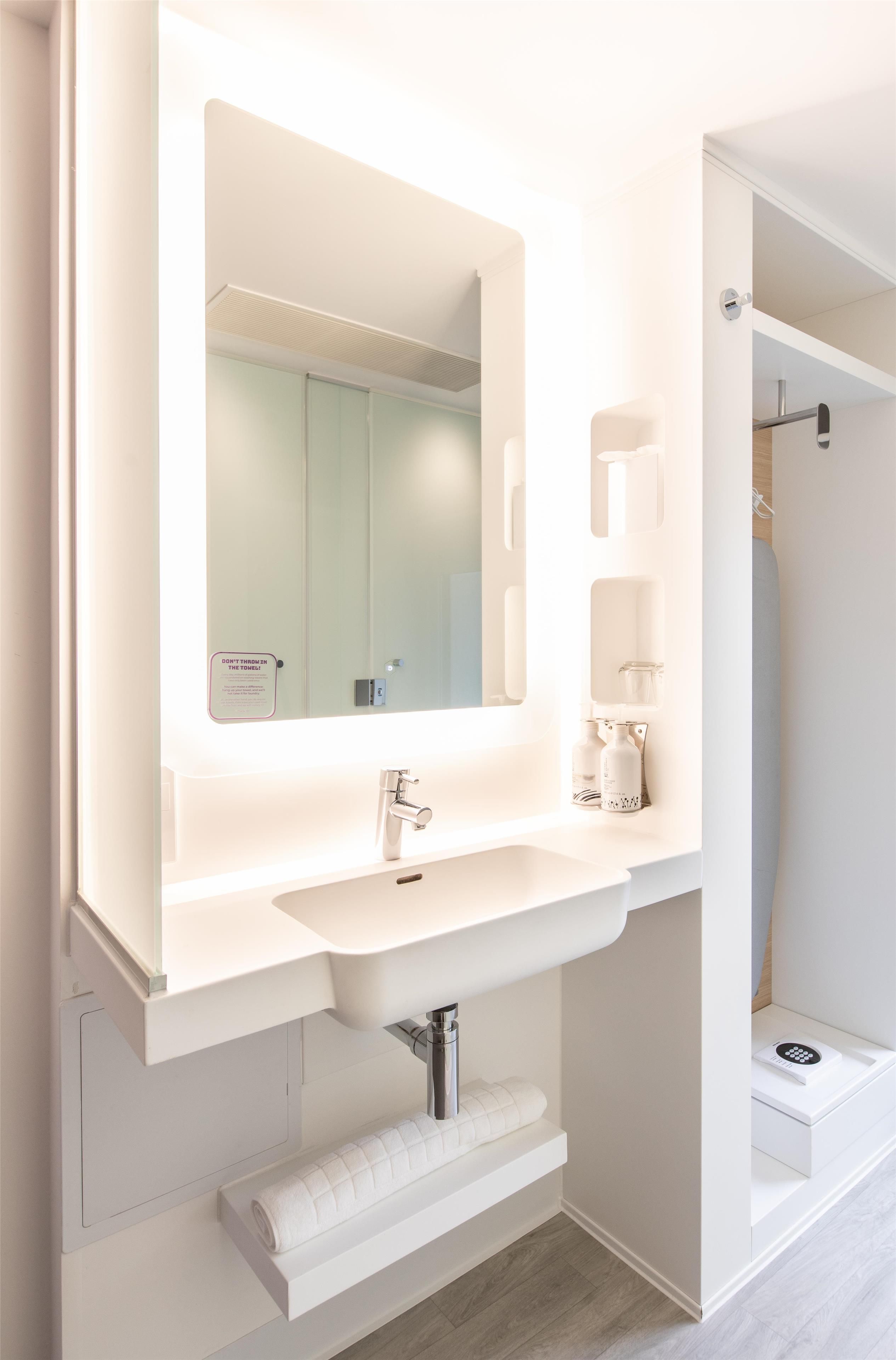 A modern bathroom with a large mirror, a sink, and a towel rack.