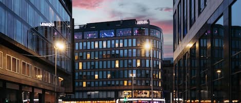 Un hotel moderno con fachada curva, ventanas amplias y un letrero visible que dice 'HOTEL'.