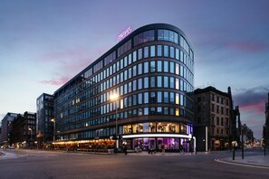 A modern hotel with a curved facade, large windows, and a prominent neon sign. - YOTEL Glasgow (Glasgow)