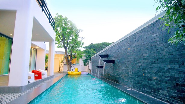 Una piscina con una pared de piedra y un flotador inflable amarillo.