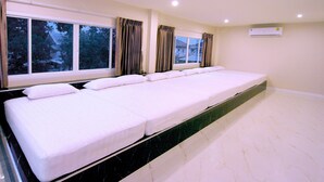Amplia habitación de hotel, limpia y bien iluminada, con una cama grande y bien tendida, ventanas amplias con cortinas y suelo de mármol.