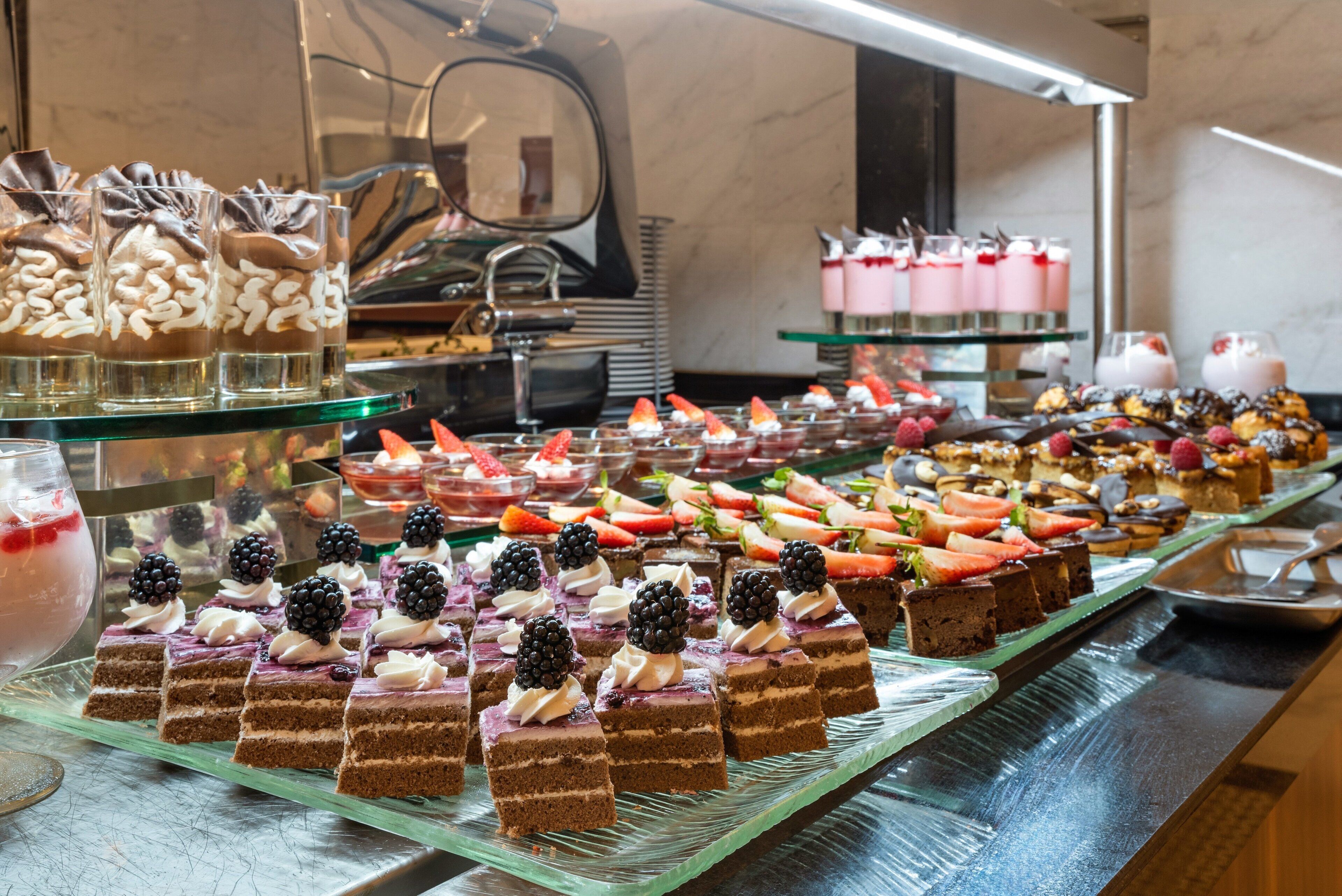 Ein Buffet mit verschiedenen Desserts, darunter Kuchen, Gebäck und Obstarrangements.