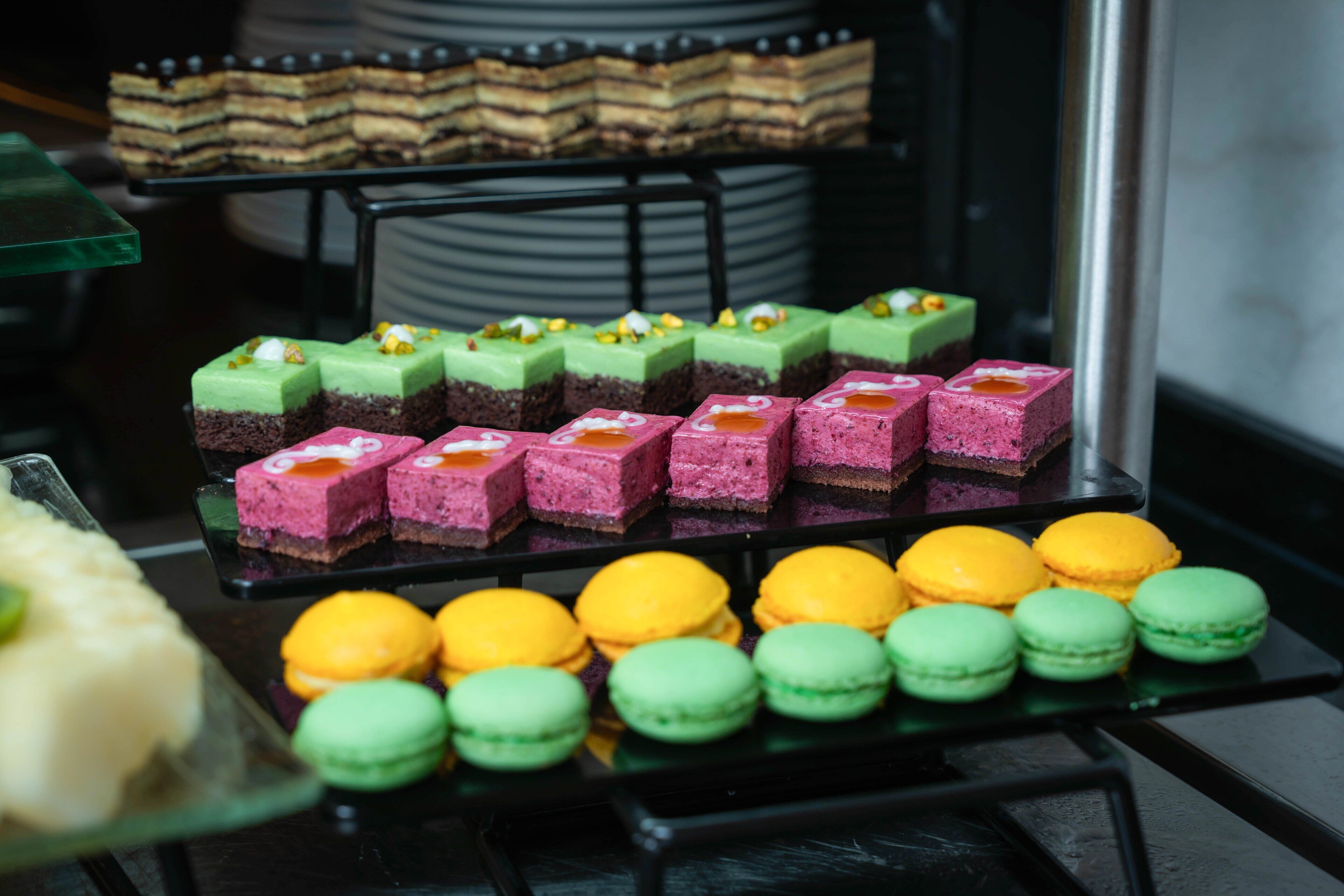 Una mesa de postres con diversos macarons de colores y pasteles en capas.