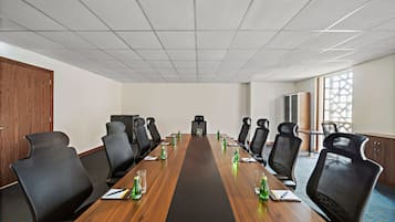A conference room with a long table, multiple chairs, and a projector screen.