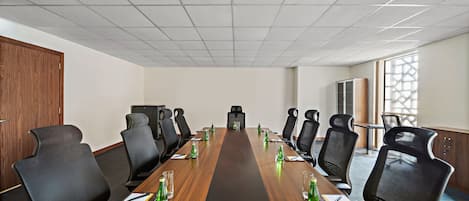 A conference room with a long table, multiple chairs, and a projector screen.