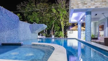 Relax by the pool surrounded by lush gardens and a unique mosaic wall.